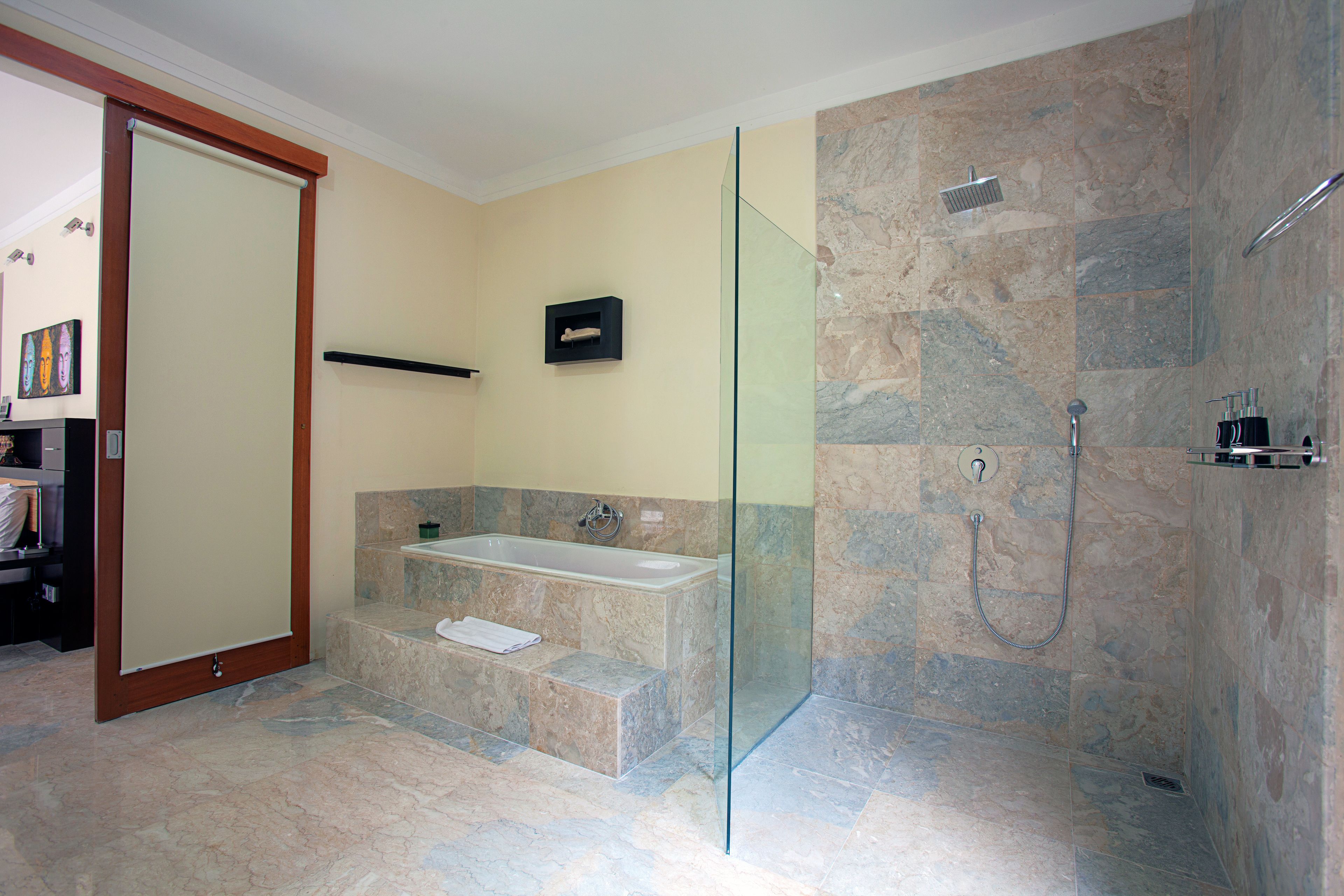 Un baño moderno con ducha de vidrio, una bañera independiente y suelo de mármol.