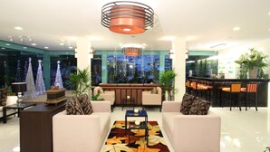 A modern lobby with a seating area, a bar, and a view of the cityscape at night. - Paradise Hotel (Udon Thani)