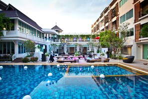 A swimming pool with a tiled deck, surrounded by lounge areas and outdoor seating. - Paradise Hotel (Udon Thani)