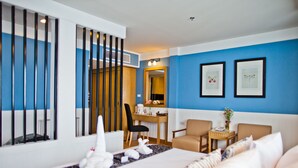 A hotel room with a bed, two chairs, a desk, and a mirror. - Paradise Hotel (Udon Thani)