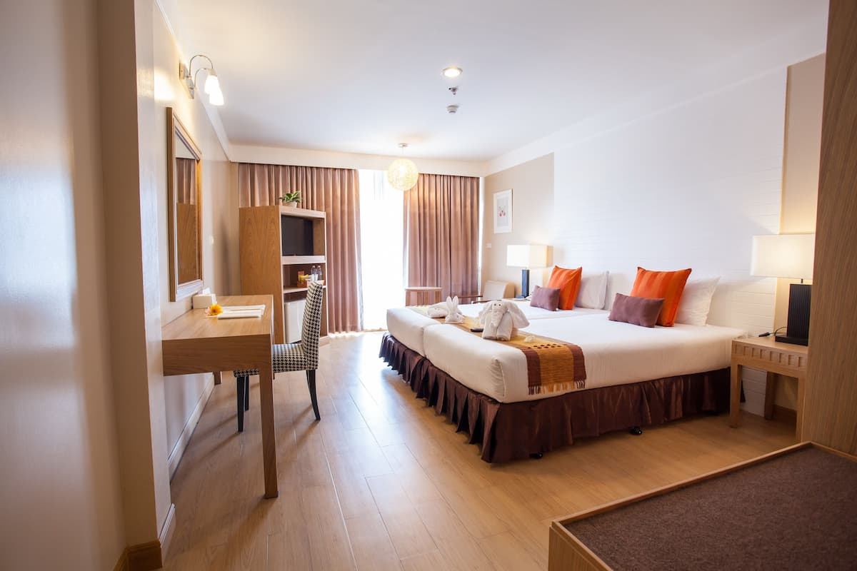 A hotel room with a bed, bedside tables, a desk, and a chair.