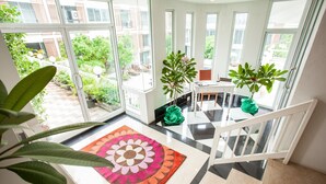 A spacious balcony with large windows, a modern staircase, and a variety of potted plants. - Paradise Hotel (Udon Thani)