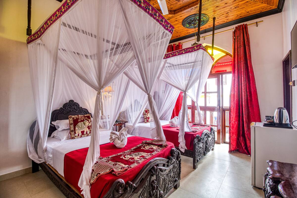 Un lit à baldaquin blanc, avec un couvre-lit rouge et des coussins décoratifs.