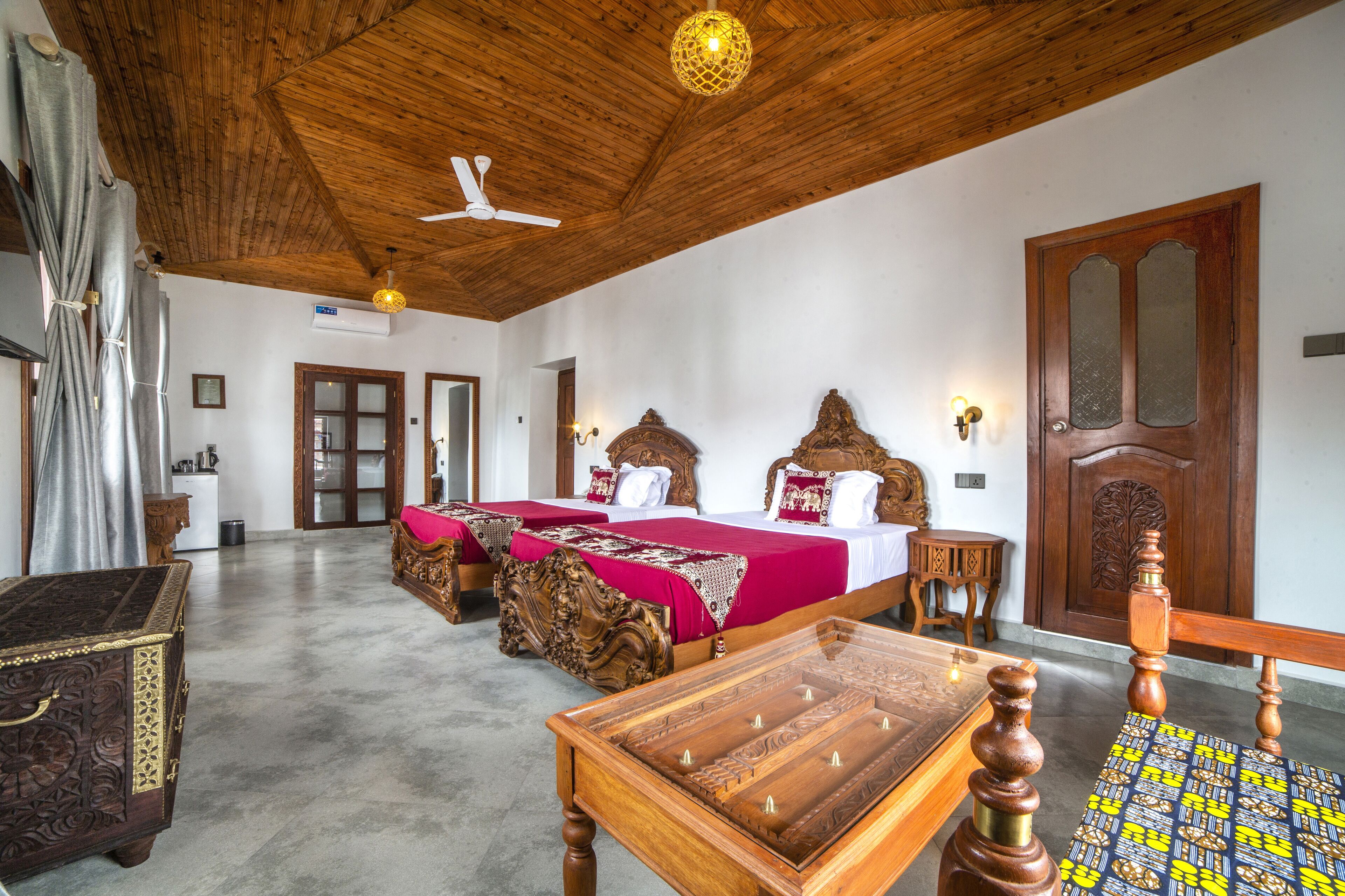 Una habitación amplia con techo alto, muebles de madera y una cama grande con ropa de cama roja.