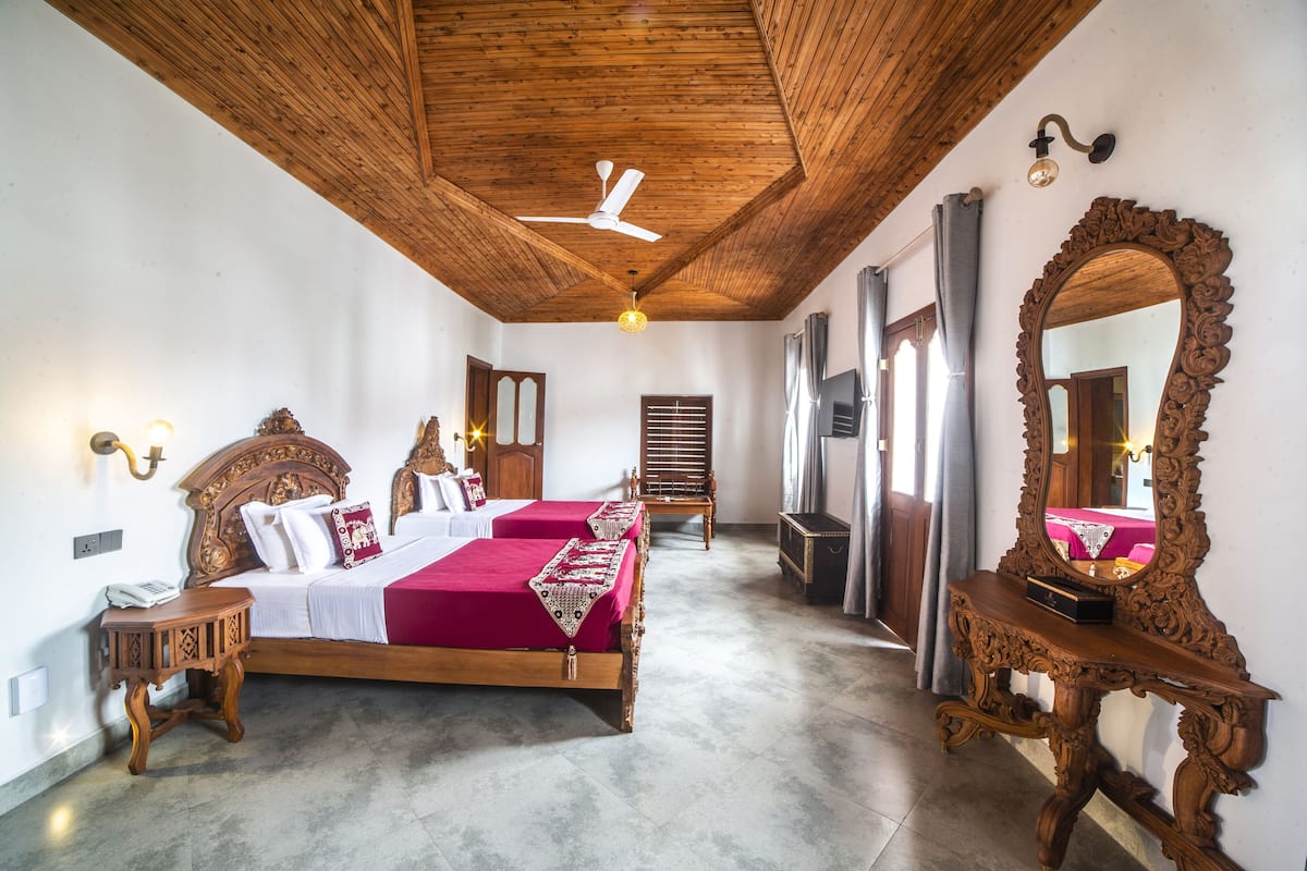 Une pièce avec un plafond en bois, un lit avec une literie rouge, un grand miroir et une table de chevet en bois.