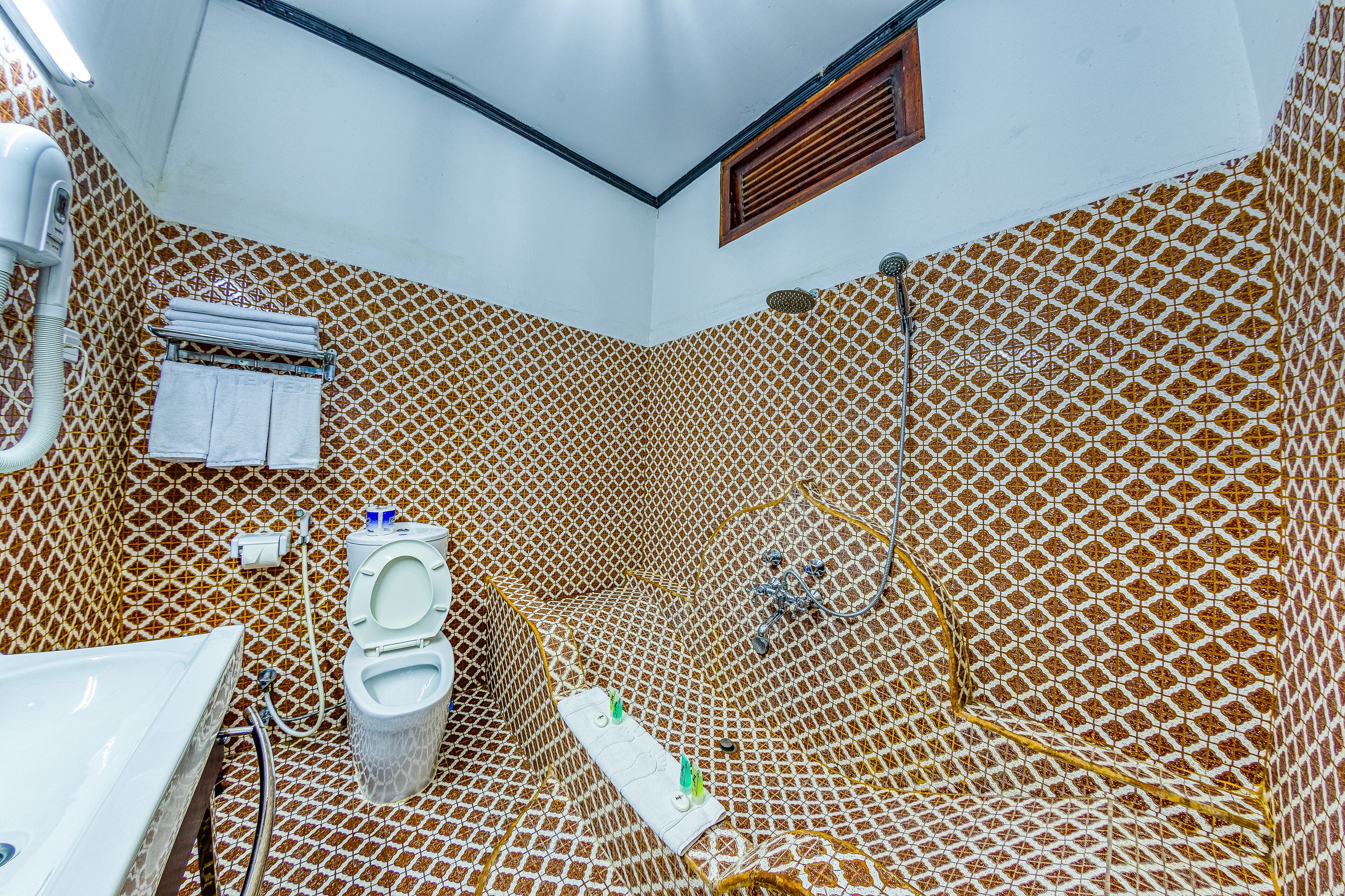 A bathroom with a patterned wall, a toilet, a sink, and a shower area.