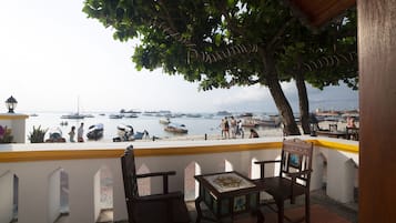 A terrace with wooden chairs and a table, overlooking a marina with boats and people.