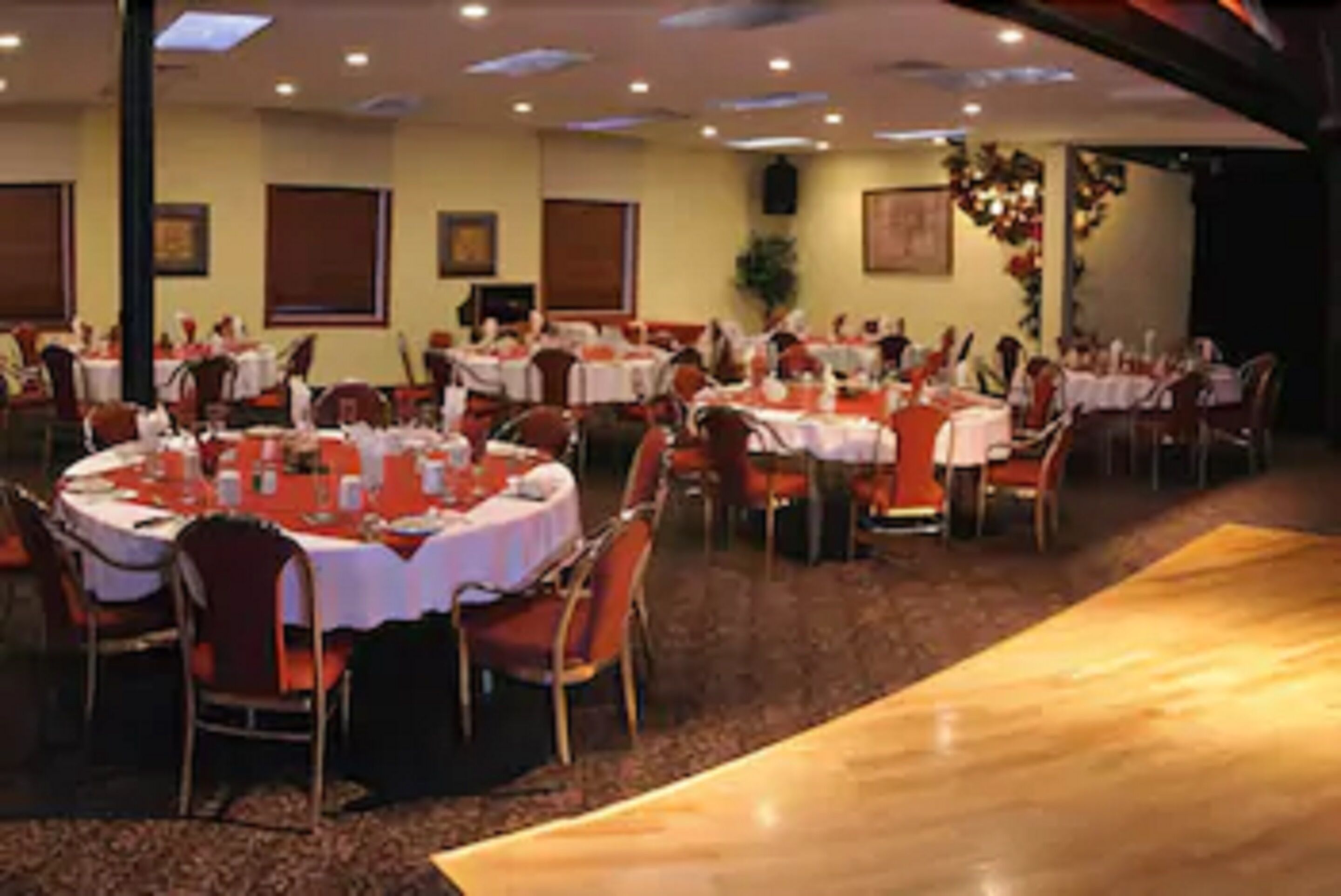 A banquet hall with round tables, chairs, and a stage area.