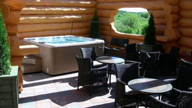 A log cabin with a hot tub, outdoor seating, and a view of the forest. - Amosphère Complexe hôtelier (Amos)