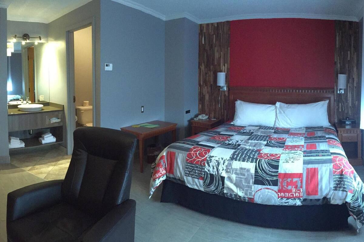A hotel room with a bed, a desk with a computer, a TV, and a bathroom.