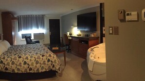 A hotel room with a bed, desk, chair, TV, and a bathroom with a bathtub and toilet. - Amosphère Complexe hôtelier (Amos)