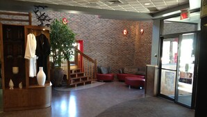 A lobby with a brick wall, a staircase, seating area, and a reception desk. - Amosphère Complexe hôtelier (Amos)