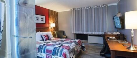 A hotel room with a bed, a desk, a chair, a TV, and a window with curtains.