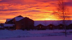 A residential area with houses and a snow-covered landscape during sunset. - Amosphère Complexe hôtelier (Amos)