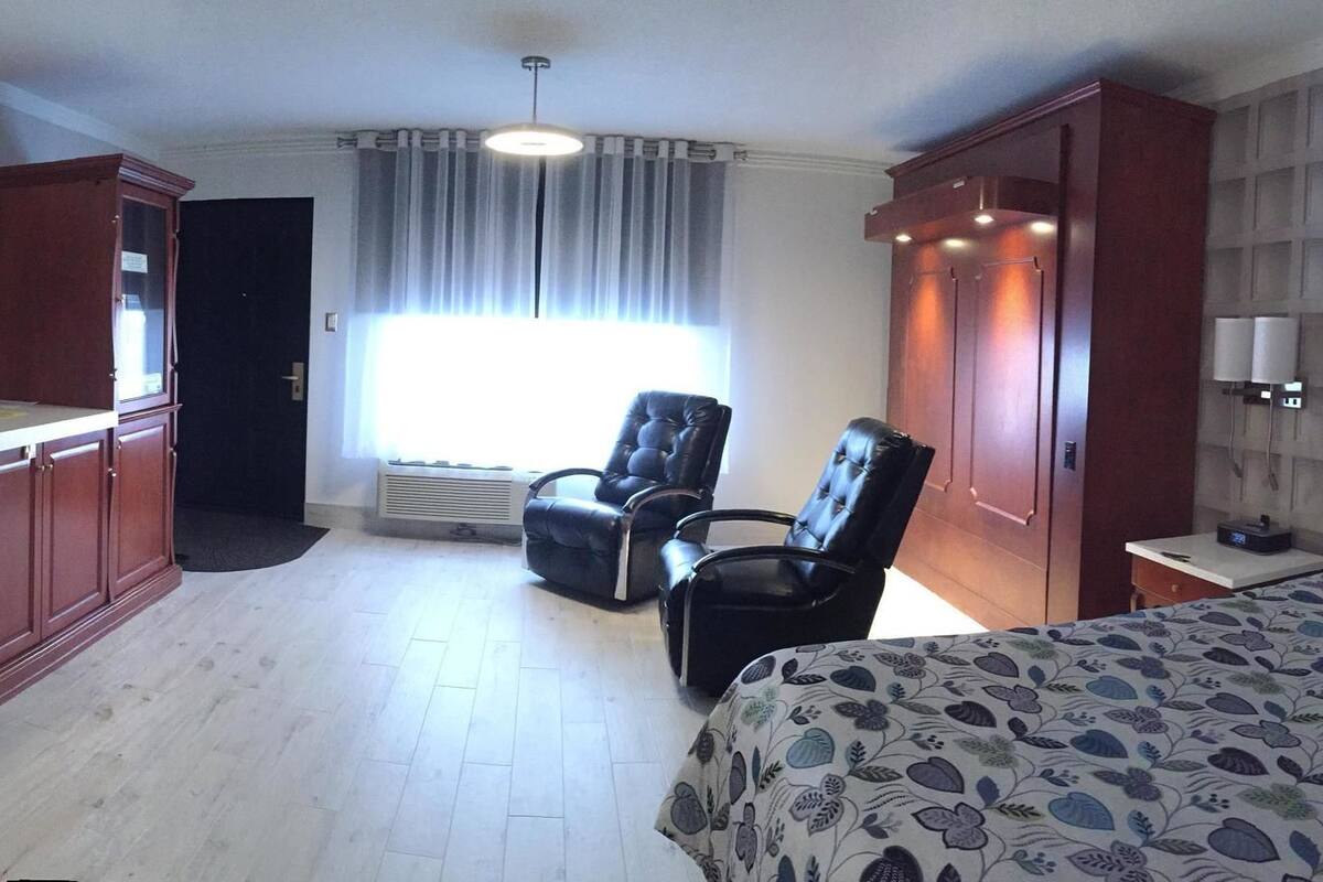 A hotel room with a bed, a desk with a computer, a chair, a TV, and a wardrobe.