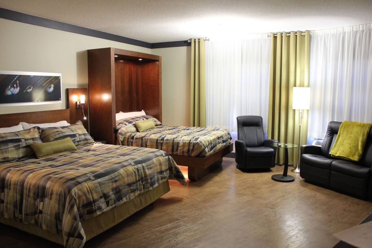 A hotel room with two beds, a sofa, a chair, and a small table.