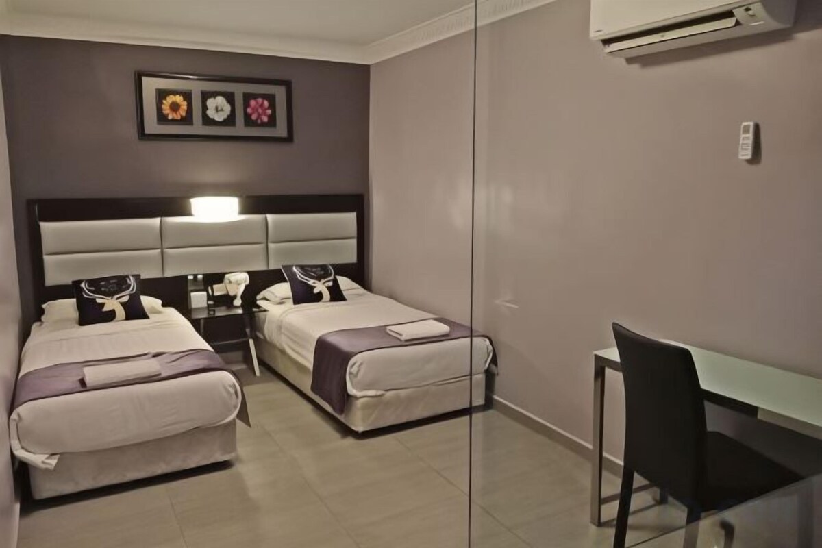 Una habitación con dos camas, un escritorio y una silla.