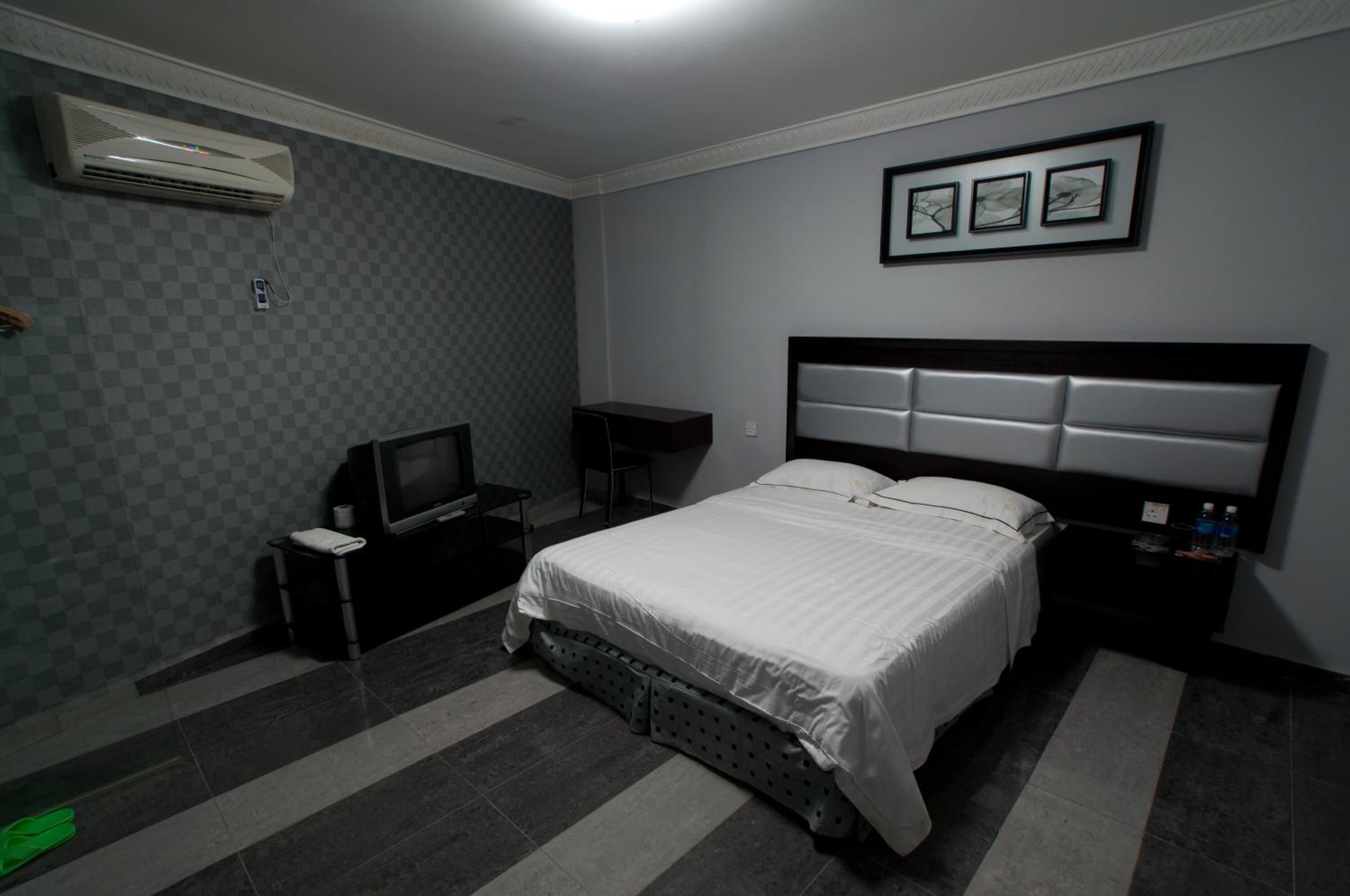Een hotelkamer met een bed, een televisie, een bureau en een airconditioning.