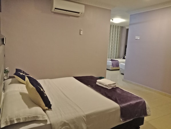 Habitación de hotel con una cama, una almohada, una manta, aire acondicionado y un baño visible al fondo.