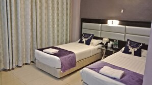 Ein Hotelzimmer mit zwei Betten, einem Nachttisch, einer Klimaanlage und einem Vorhang.