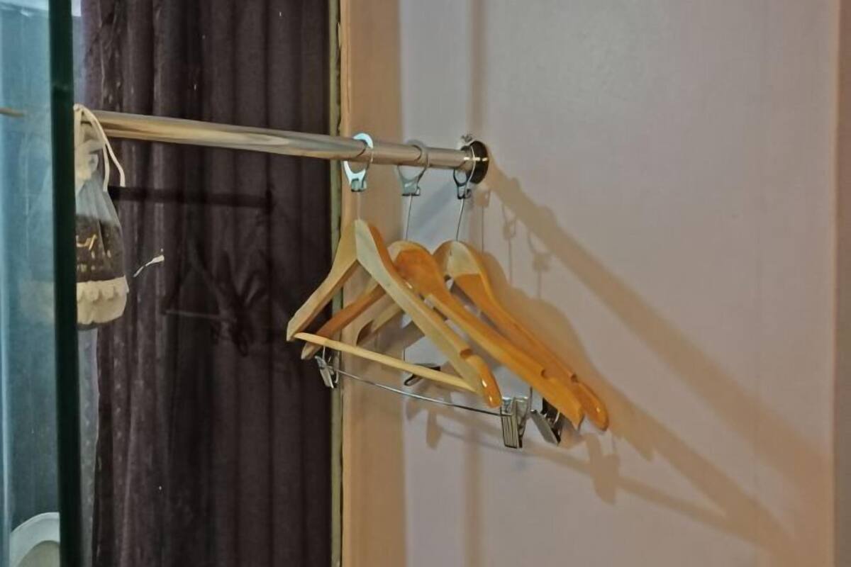 Un perchero metálico con perchas de madera contra una pared.