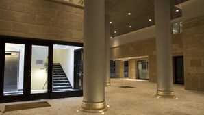 A spacious lobby with a central staircase, large columns, and a modern design. - MyApART Suite (Rome)