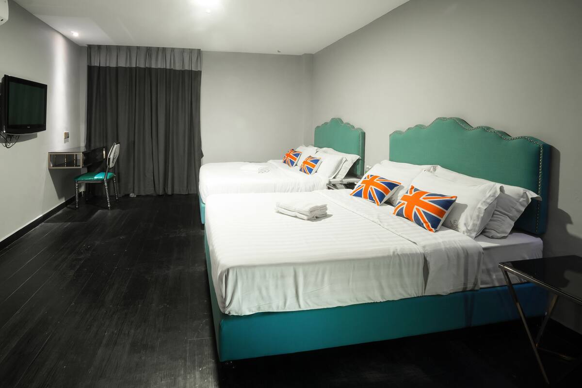 Ein Hotelzimmer mit zwei Betten, einem Fernseher, einem Schreibtisch und einem Sessel.