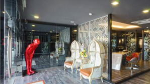 Een modern interieur met een glazen scheidingswand, een rode sculptuur en klassieke stoelen met vazen.