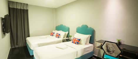 A hotel room with two beds, a desk, a chair, and a TV.