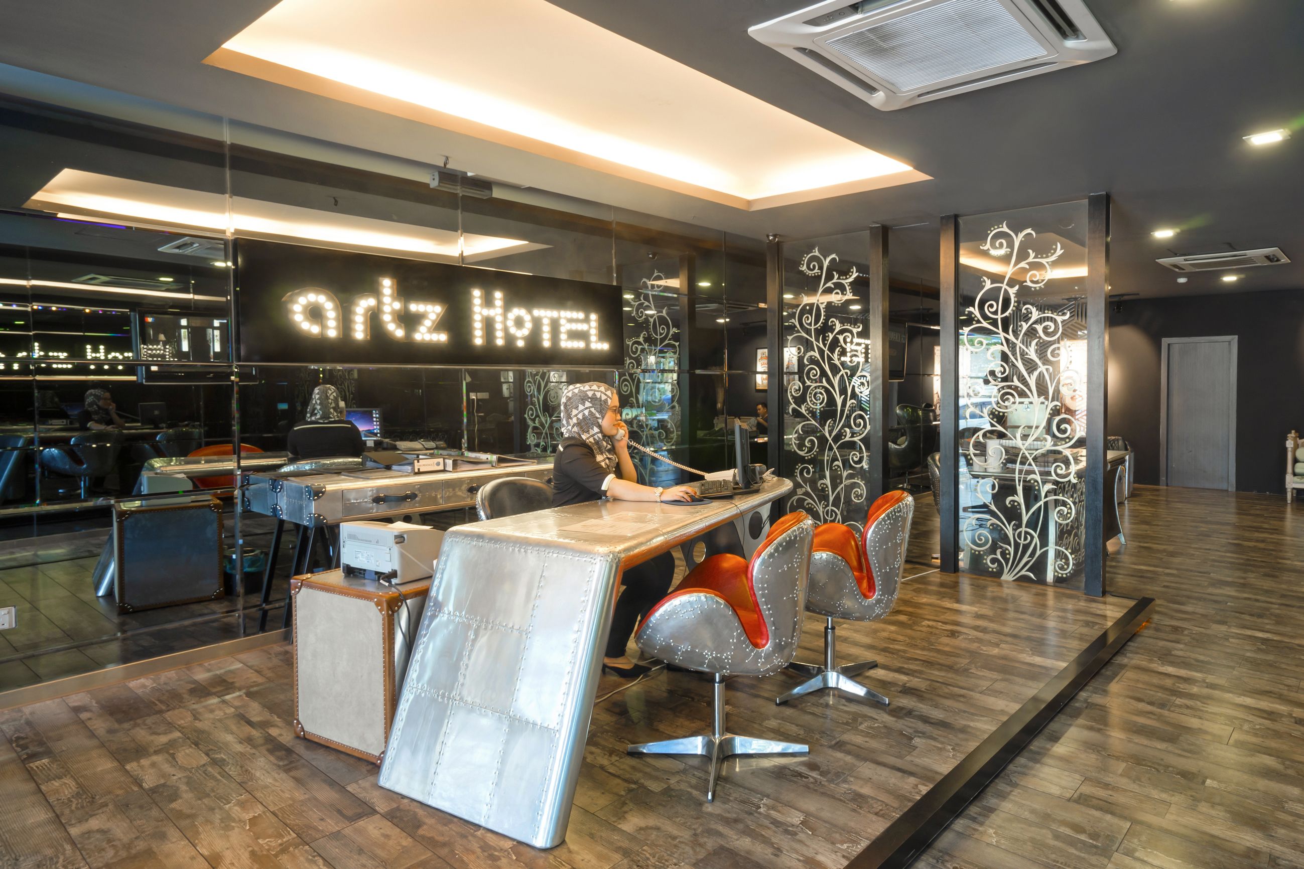 A modern hotel interior with a reception desk, seating area, and a visible bar area.