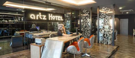 A modern hotel interior with a reception desk, seating area, and a visible bar area.