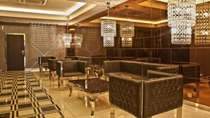 A modern lobby with plush seating, reflective flooring, and ornate chandeliers.