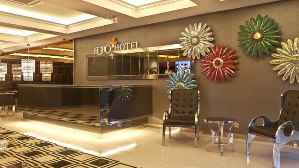 A hotel reception area with a modern design, featuring a reception desk, seating area, and decorative wall art.