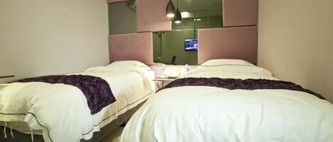 A hotel room with two beds, a television, and a mirror on the wall.