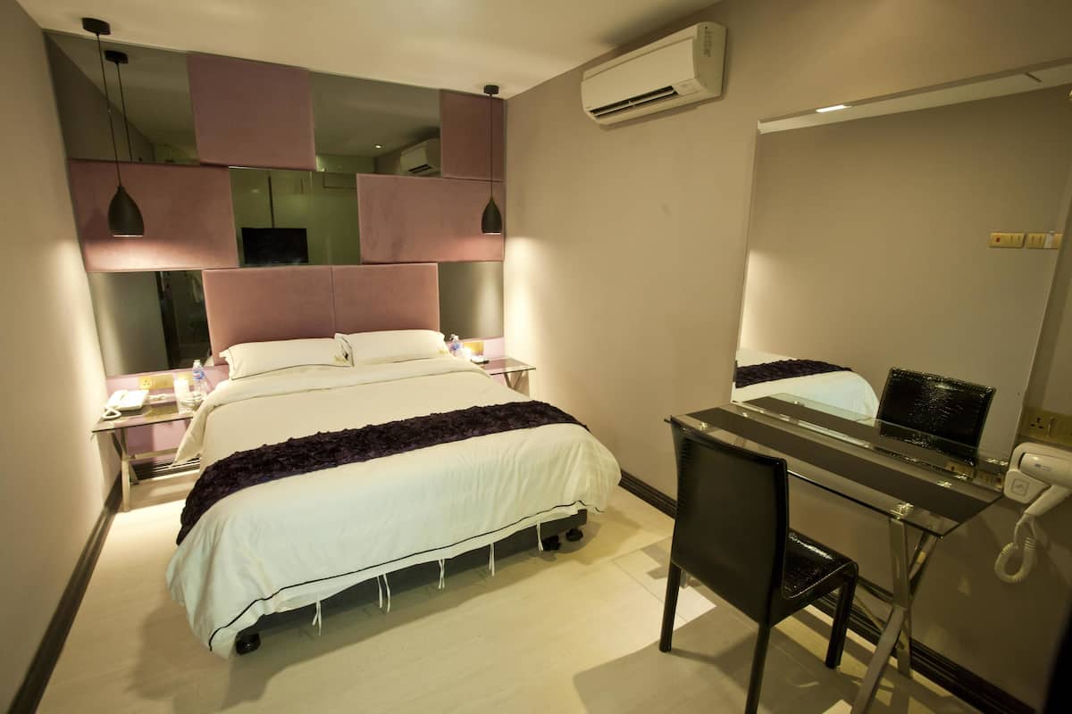 Una habitación de hotel con cama, escritorio, silla y espejo.