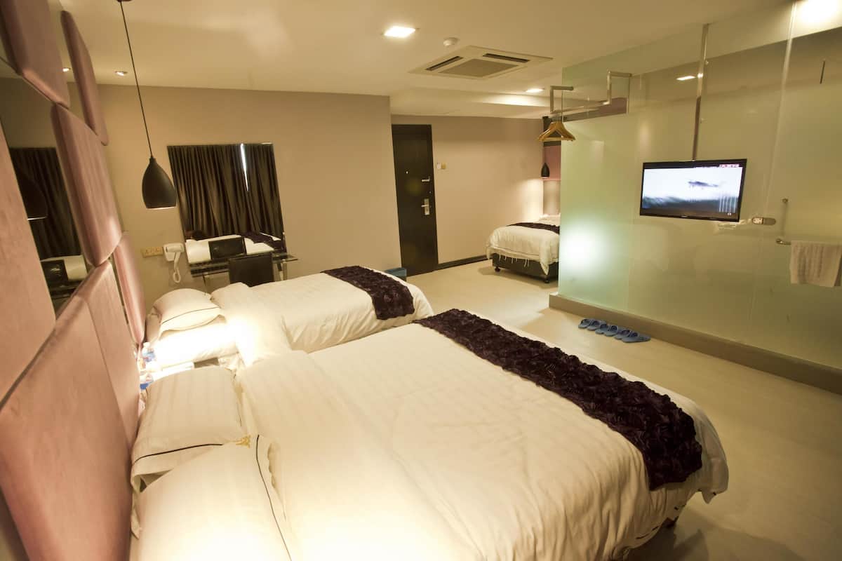 Habitación de hotel con dos camas, televisor, escritorio y silla, y un espejo.