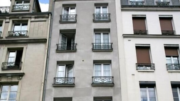 A hotel facade with multiple floors, balconies, and a storefront with visible signage for 'debitel' and 'SFR'. - Sully Hôtel (Paris)