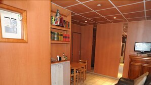 A compact living space with a kitchenette, a dining area, and a television. - Sully Hôtel (Paris)
