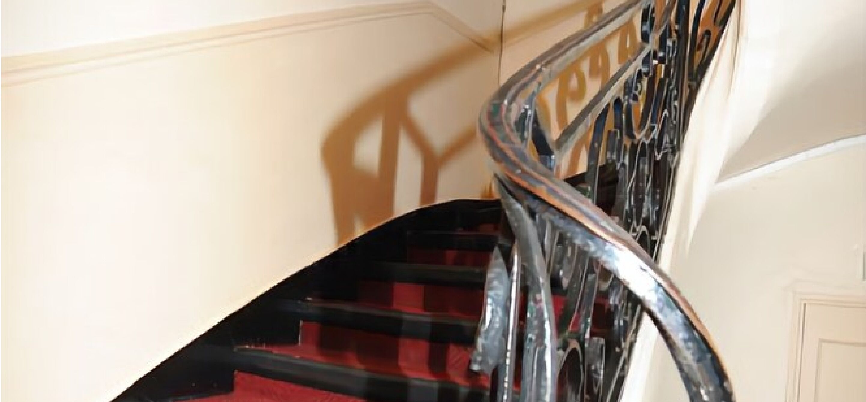 Una scala con ringhiera nera e tappeto rosso.