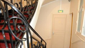A staircase with ornate black metal railings and red carpeted steps. - Sully Hôtel (Paris)