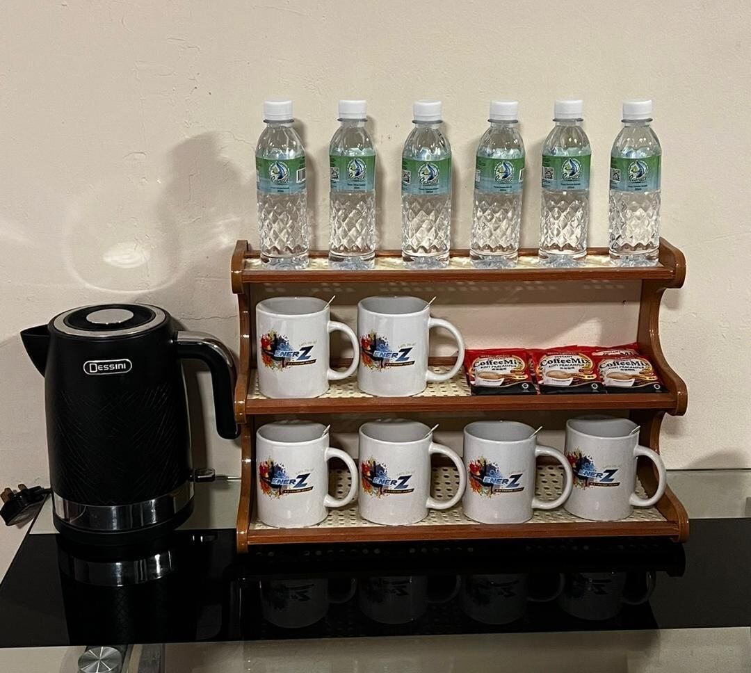 Un coin café équipé d’une machine à café, de bouteilles d’eau et de tasses à café, le tout placé sur une étagère.