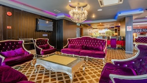 Un hall d’entrée luxueux, avec des canapés en velours violet, un lustre et un sol à carreaux.