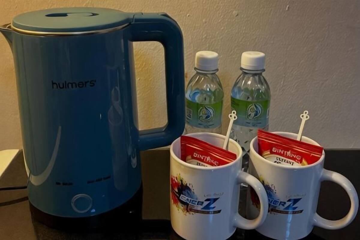 A blue electric kettle, two bottles of water, and two mugs with a beverage brand.