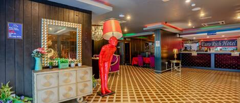 Zona de recepción con mostrador de check-in, un maniquí decorativo y piso estampado.