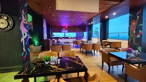 A modern restaurant with a bar area in the background, featuring a mix of seating arrangements and a view of the cityscape. - Regenta Central Grand Exotica Pune (Pune)
