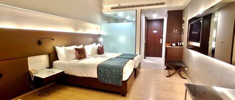 Una habitación de hotel moderna con una cama grande, una mesita de noche y un televisor montado en la pared.