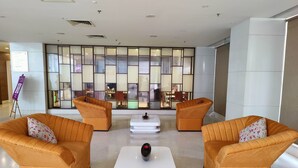 A lobby with two orange armchairs, a white coffee table, and a large window with a view of the interior. - Regenta Central Grand Exotica Pune (Pune)