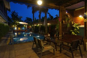 An outdoor pool area with wooden deck seating and a tiled pool.