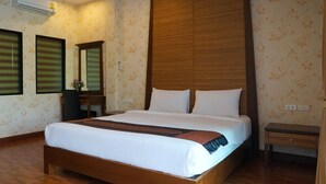 Una cama bien hecha con cabecera de madera, una mesita de noche y un aire acondicionado instalado en la pared.