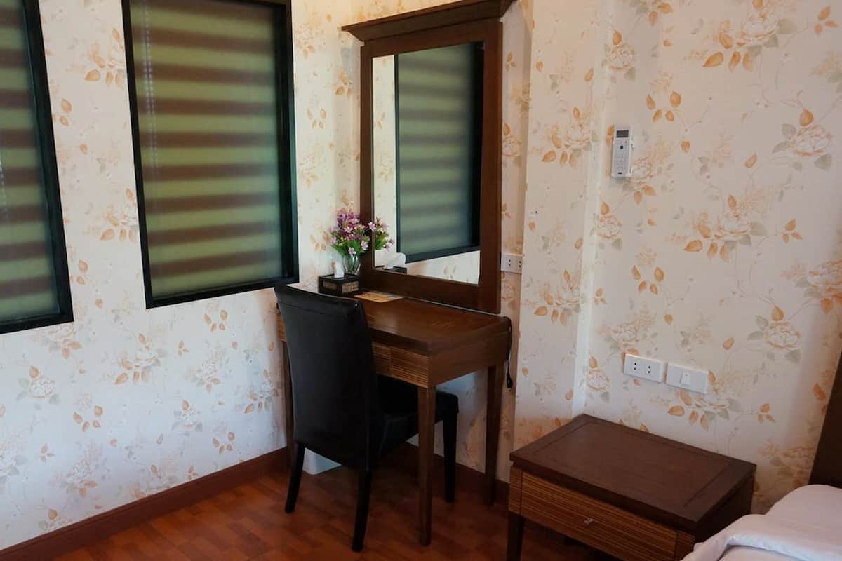 A bedroom with a wooden desk, a chair, a bedside table, and a bed.